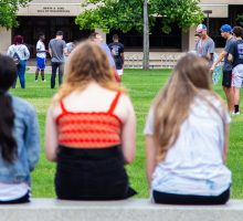 Students sitting on a wall, watching activities on the quad