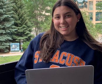 Pre-college student sitting outside with a laptop