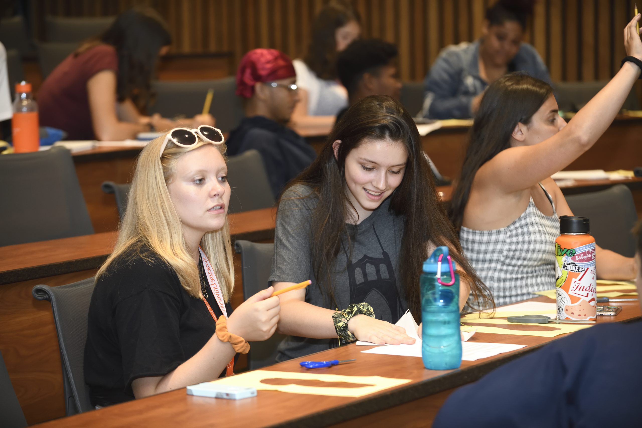 Summer classes for high schoolers Several Summer College - On Campus students sitting in a lecture hall, taking notes.