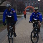Two people riding bikes on campus