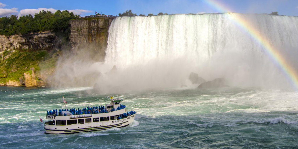 A boat with the words "Maid of the Mist" on the side, sailing by the falls at Niagara Falls.