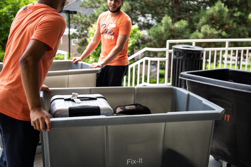 Grey tote bins pushed by resident advisors on move-in day for Summer College - On Campus 