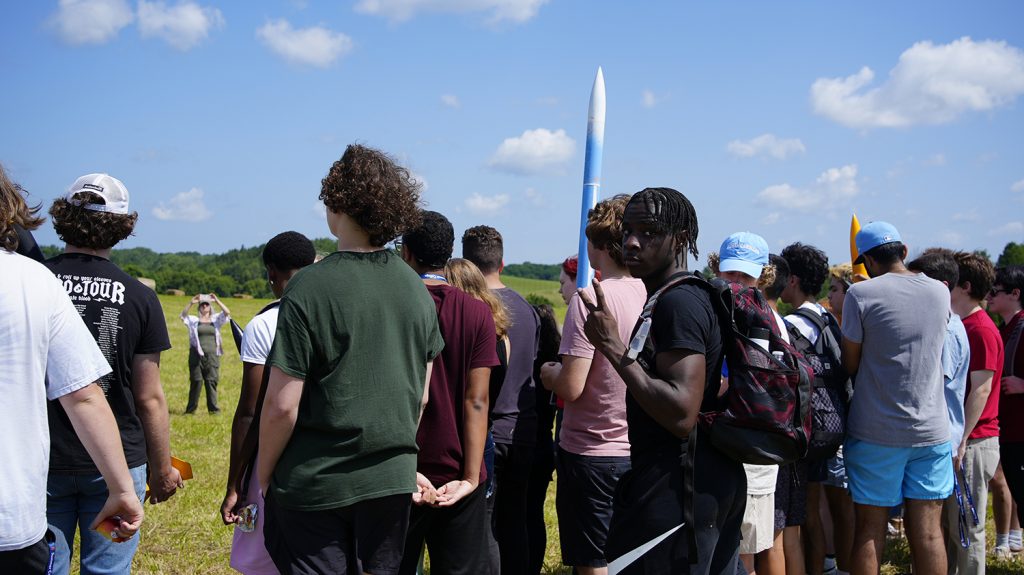 Summer College students participate in an Aerospace Engineering class outside on a large field.