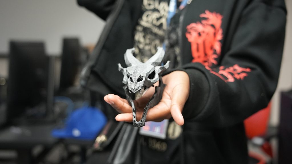 A Summer College student shows off a dragon made in the makerspace and 3D printing class. 